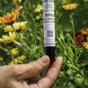 hand holding a tube of rolled joints in a bush of calendula