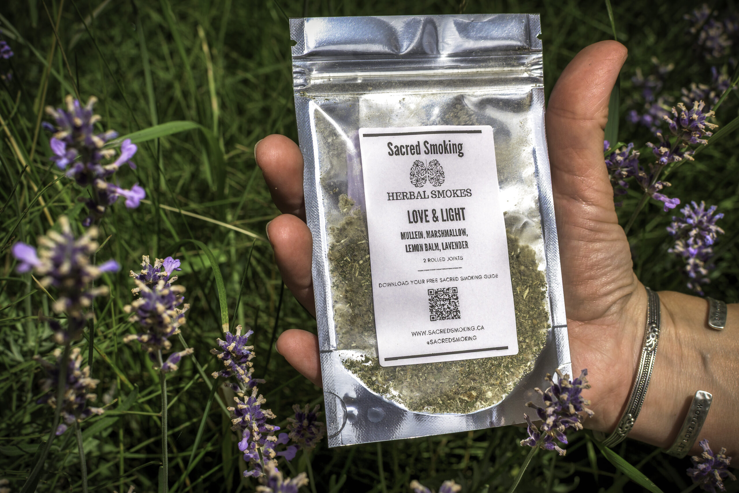 hand holding a pouch of loose herbs in a bush of lavender